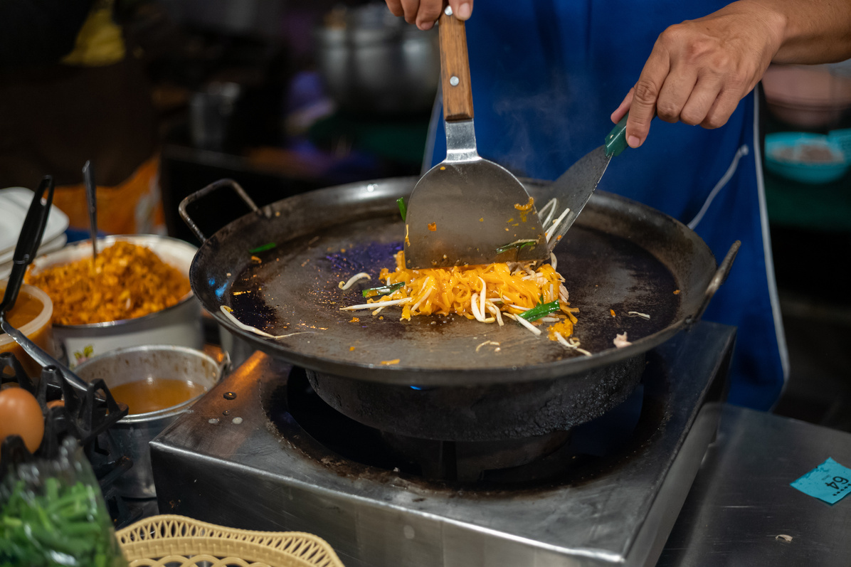 Thai street food vendor preparing Thai street food pad thai at market stall